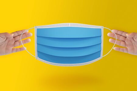 Hand picked surgical mask protect virus coronavirus covid 19 on yellow isolated background.の写真素材