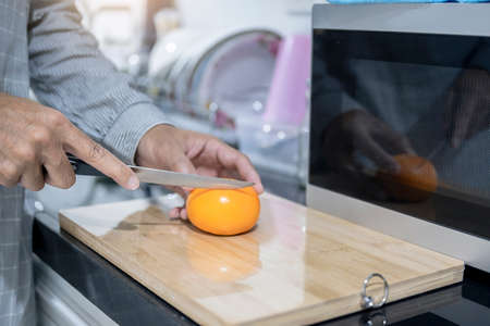 Blurred man asian cooking in kitchen of home He hands cutting vegetables and cutting fruit in the kitchen   to great hand on microwave in kitchen blurred backgroundの写真素材