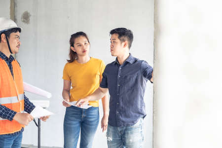 Young asian couple checking house with foreman engineering home inspection building house Walk home inspection with looking and pointing construction for check building home on job site to construction 2021の写真素材