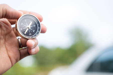 Man hand holding compass on city and car blurred background Using wallpaper or background travel or navigator image.の写真素材