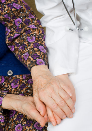 Elderly woman holds the doctor's hands.の写真素材