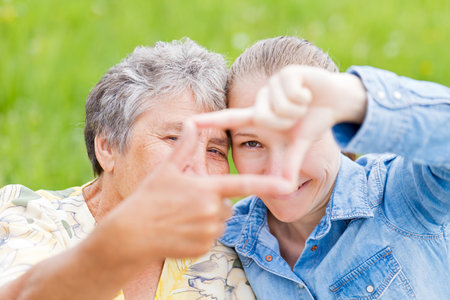 Elderly woman and her daughter framing  their facesの写真素材