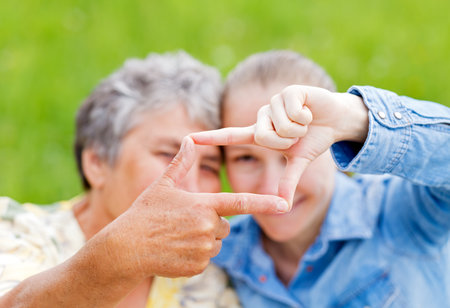 Elderly woman and her daughter framing  their facesの写真素材
