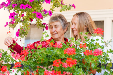 Elderly woman shows her flowers to her assistantの写真素材