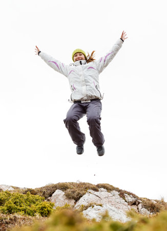 Happy young girl jumping from a rock