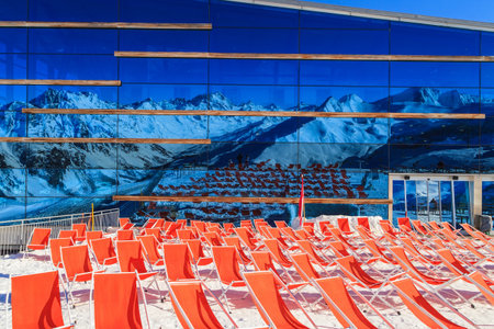 Deckchairs and mountains reflected on the restaurant wallの写真素材