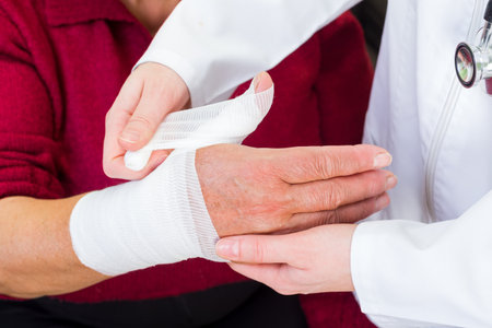Photo of doctor bandaging the elderly woman thumbの写真素材