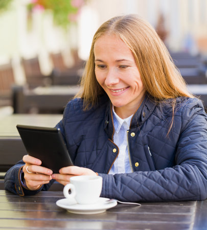Young blonde woman reading the news in coffee break