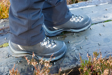 Close up photo hiking boots on studded wooden footbridge