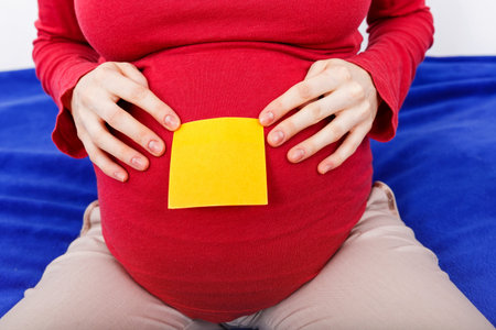 Close up photo of sticky note on pregnant woman bellyの写真素材