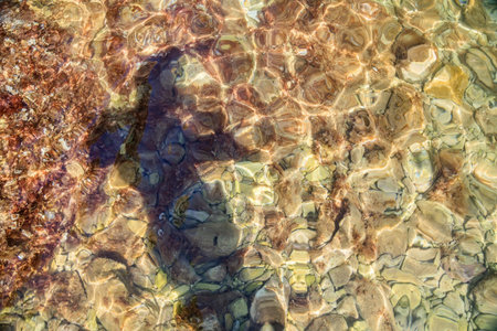 Human body shadow in water on rocky seasideの写真素材