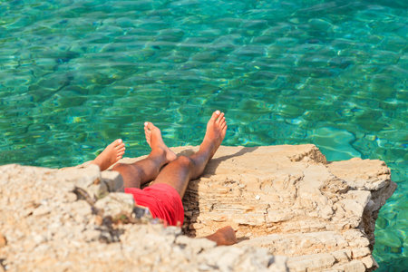 Young tourists sunbathe on mediterranean rocky beachの写真素材