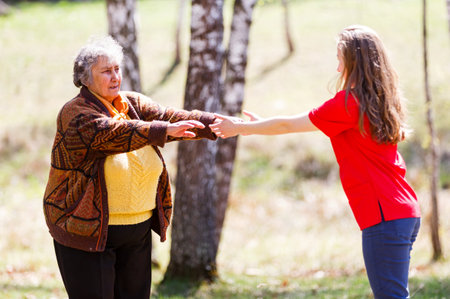 Elderly woman and young caregiver walking in the parkの写真素材