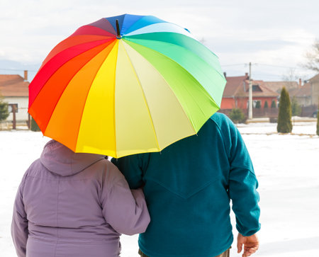 Elderly couple walking in the park with colorful umbrellaの写真素材