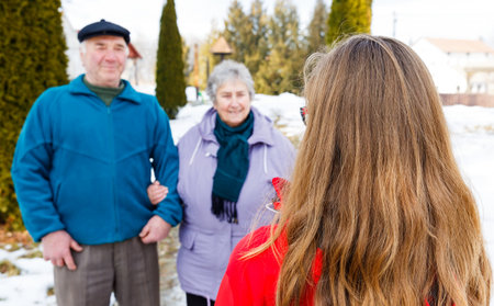 Elderly couple and young caregiver walking in the park in wintertime
