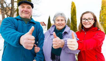 Happy elderly couple and young caregiver showing thumbs upの写真素材