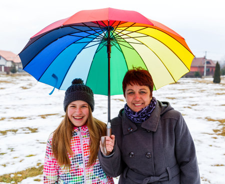 Photo of happy mother with daughter under colorful umbrellaの写真素材
