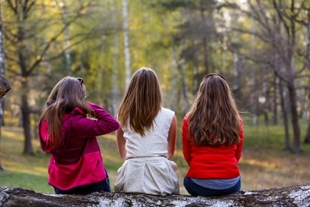 Young ladies sitting on tree trunk in the forestの写真素材
