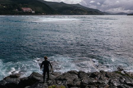 Surfer looking at the sea with wetsuit and surfboardの写真素材