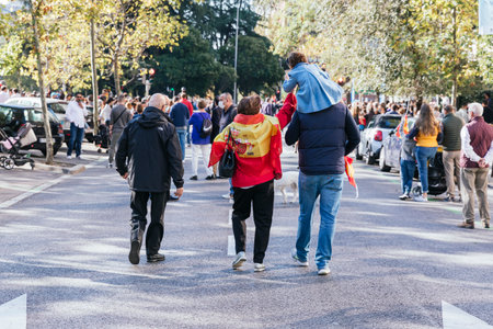 Family walking and mother with the Spanish flag around her neck as if it were a cape at the military parade of the National Day of Spain on October 12 - Madridのeditorial素材