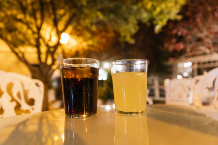 Terrace table in the evening with two drinking glasses, coke and lemon without peopleの写真素材