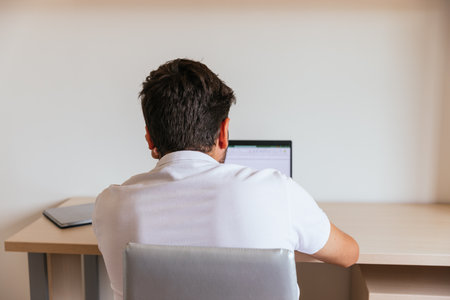 Young man sleeping on the table in front of the computer leaning on his arms, with a coffee, a...