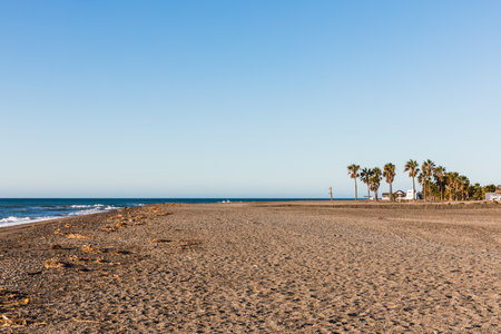 Uncrowded pebble beach at sunrise with cloudless blue sky in Motril, Andalusia Spainの写真素材
