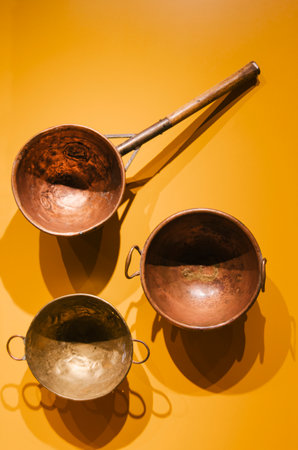 three antique pan, brass and copper holes on a yellow backgroundの写真素材