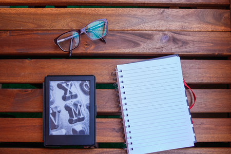 Ebook, glasses and notebook on wooden table. Save paper and ecology