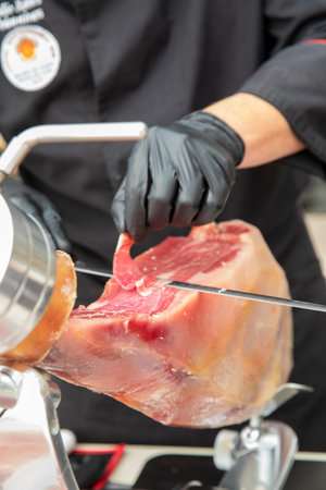 Vertical photo of a professional ham cutter cutting an Iberian ham.の写真素材