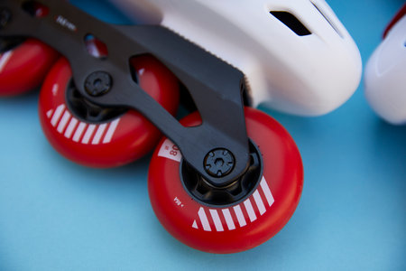 Close-up of the front wheel of white inline skates on a blue background with copyspaceの写真素材