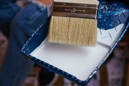 Close-up unrecognizable woman's hands with purple gloves taking paint with a brush in a tray. Reformsの写真素材