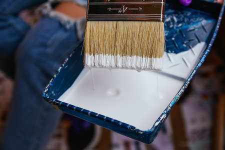 Close-up unrecognizable woman's hands with purple gloves taking paint with a brush in a tray. Reformsの写真素材