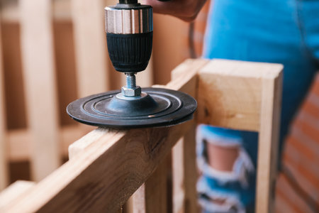 Close-up of two hands of an unrecognizable woman sanding a pallet with an electric sander. home renovationの写真素材
