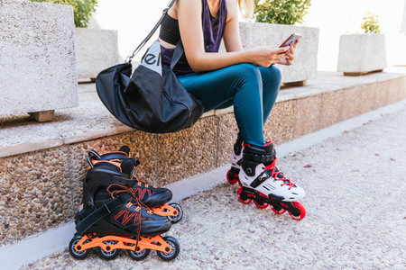 unrecognizable young girl getting ready with her mobile phone and her bag to go out on inline skates.の写真素材