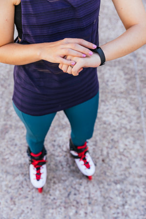unrecognizable young girl getting ready on her smartwatch to go out on inline skatesの写真素材