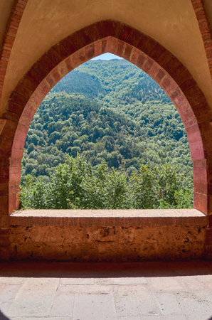 window in the vaults of a mountain abbey with green forest in the backgroundの写真素材