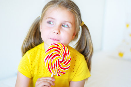 Funny child with candy lollipop, happy little girl eating big sugar lollipop, kid eat sweetsの写真素材