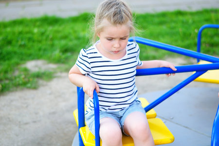 Adorable sad little girl on carouselの写真素材