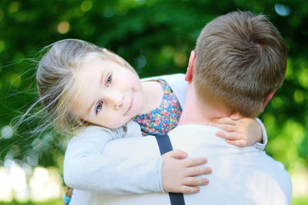 Happy adorable little girl hugging embracing her fatherの写真素材