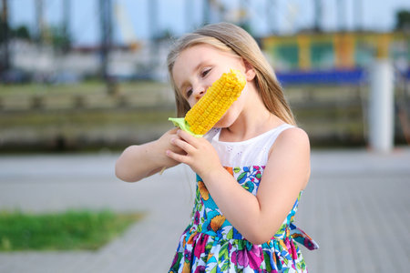 Adorable funny girl eating corn on the cobの写真素材