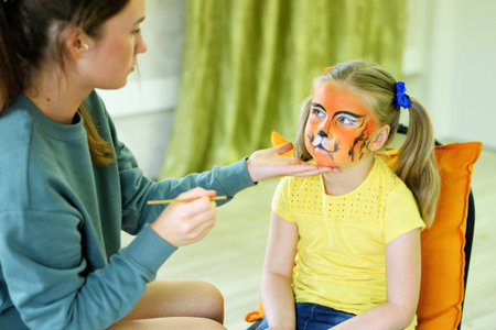 Adorable little girl getting her face painted like tiger