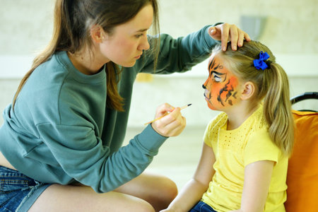 Adorable little girl getting her face painted like tigerの写真素材