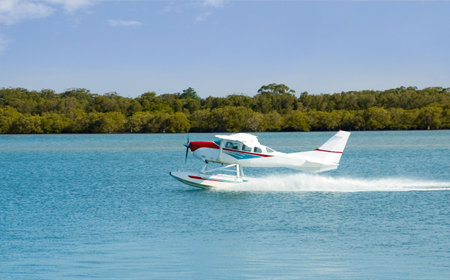 A floating Seaplane speeds up to take off on a sightseeing excursion on the New South Wales Coast,...