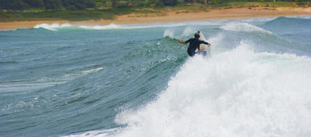 landscape Side shot of a surfer as he cuts back on the crest of a huge wave, the surf starts to...