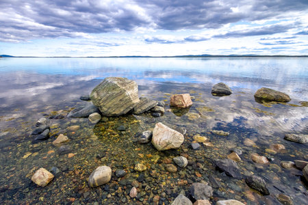 Stones on the shore of the Kandalaksha Bay of the White Sea. Sky reflected in waterの写真素材