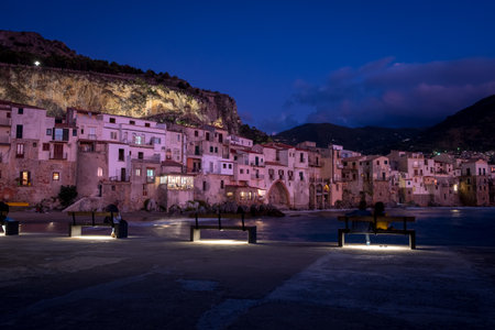 View on habour and old houses in Cefalu at night, Sicily. couple of people resting on a benchの写真素材