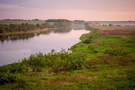 Sunny summer landscape with river.Green hills and meadows.Fields of ripe wheat.