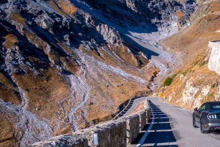 Sports car before a sharp bend on a mountain road Passo Dello Stelvio,autumn landscape, Dolomites, Italyの写真素材