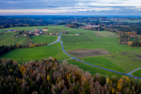 Aerial view Autumn landscape in Bavaria near Miesbach. Road going into the distance and the peaks of the Alps on the horizon. Clouds sky, Yellow trees and green fieldの写真素材